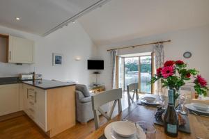 a kitchen and living room with a table with a vase of flowers at 2 Bed in Porthleven oc-quaysi in Porthleven +8 photos