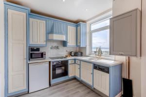 a kitchen with blue and white cabinets and a window at 3 Bed in Aberdovey oc-v29263 in Aberdyfi