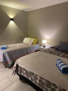 a bedroom with two beds and a lamp on a wall at Punta Luna in La Serena