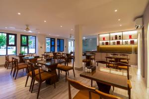 a restaurant with wooden tables and chairs and windows at Palago Binh Thanh Hotel in Ho Chi Minh City
