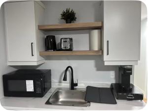 a kitchen counter with a sink and a microwave at Cozynest in Moncton