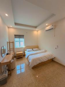 a bedroom with a bed and a desk and a window at Tay Bac Hotel in Mộc Châu