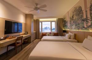 a hotel room with two beds and a desk and a tv at Palago Binh Thanh Hotel in Ho Chi Minh City +24 photos