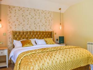a bedroom with a large bed with a yellow bedspread at Bumblebee Cottage-Uk39918 in Ballakinnag +25 photos