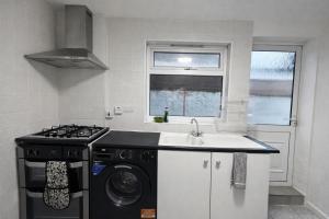 a kitchen with a washing machine and a sink at 4-Bed House in Enfield- Sleeps 8- Private garden in Enfield