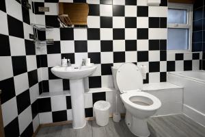 a bathroom with a black and white checkered wall at 4-Bed House in Enfield- Sleeps 8- Private garden in Enfield +19 photos