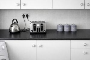 a kitchen counter with a toaster and mugs on it at 4-Bed House in Enfield- Sleeps 8- Private garden in Enfield