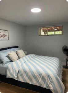 a bedroom with a bed with blue and white stripes at Cozynest in Moncton