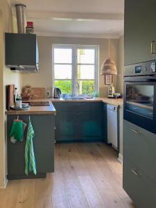 a kitchen with blue cabinets and a sink and a stove at Charming Farmhouse With Views On Møn in Borre