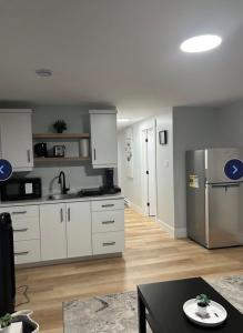 a kitchen with white cabinets and a stainless steel refrigerator at Cozynest in Moncton +24 photos