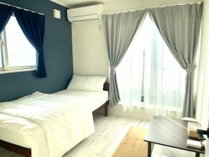 a bedroom with two beds in front of windows at Sunny Inn Sumida in Tokyo