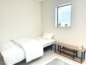 a white bedroom with a bed and a table at Sunny Inn Sumida in Tokyo