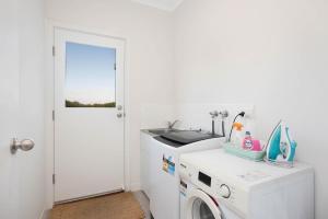 a white laundry room with a sink and a washing machine at Beach by the Dunes in Goolwa South +24 photos