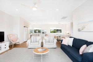a living room with a blue couch and white chairs at Beach by the Dunes in Goolwa South