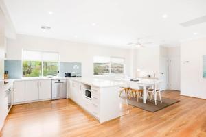 a white kitchen with a table and a dining room at Beach by the Dunes in Goolwa South