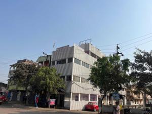 a tall building on a city street with trees at Hotel O Sri Ram Guest House in Kendrāparha