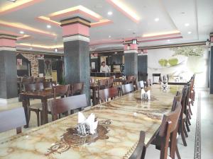a restaurant with a long table and wooden chairs at Hotel Rising Sun in Bacha +12 photos