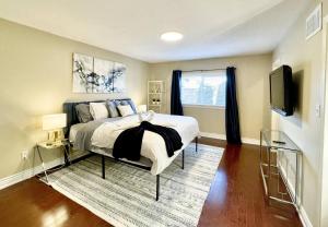 ein Schlafzimmer mit Bett und Flachbildfernseher in der Unterkunft Maison Laurier, Modern 5B4B Home Inc BSMT Free parking, Close to trails in Richmond Hill
