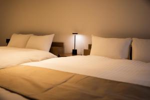 two beds with white sheets and a lamp in a room at StaySpring HARUYOSHI in Fukuoka