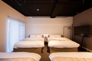a room with four beds and a flat screen tv at StaySpring HARUYOSHI in Fukuoka