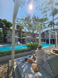 a man sitting on a striped blanket next to a swimming pool at Treevana Club Chiangmai in Chiang Mai +108 photos