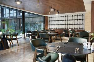 a restaurant with tables and chairs and windows at Afrosiyob Regency Hotel in Tashkent
