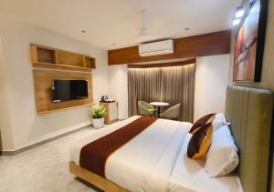 a bedroom with a large bed and a tv at Mayo Suites in Palakkad