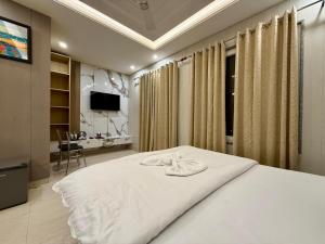 a bedroom with a white bed and a desk at Hotel Vaidik Ganga in Rishīkesh