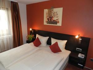 1 dormitorio con 1 cama blanca y 2 almohadas rojas en Garni Hotel Moselschild, en Ürzig