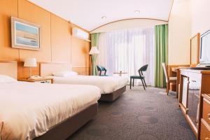 a hotel room with two beds and a desk at Blancvert Nasu Onsen Hotel in Nasu