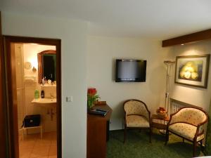 um quarto de hotel com duas cadeiras e uma mesa e uma televisão em Garni Hotel Moselschild em Ürzig