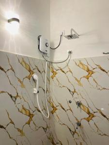 a shower in a bathroom with a brown and white marble wall at Hasara Homestay in Dickwella