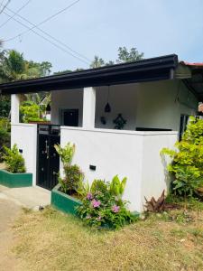 a white house with plants in front of it at Hasara Homestay in Dickwella