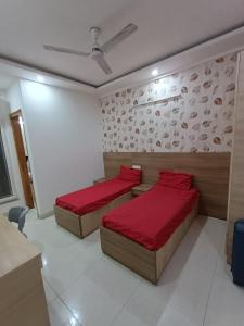two beds in a room with red sheets at The Elite Ambience Hotel in Greater Noida +8 photos