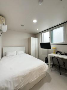 a white bedroom with a white bed and a desk at Three Seven Hotel Dongdaemun in Seoul