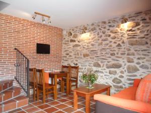 a living room with a stone wall and a table and chairs at Baelo Claudia in Navalguijo