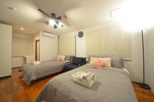 a bedroom with two beds and a ceiling fan at Sobe House in Yomitanson in Yomitan
