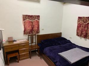 a bedroom with a bed and a desk and curtains at Scarecrow Homestay in Jincheng