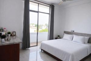 a bedroom with a white bed and a large window at Sky Glow Residence in Pepiliyana