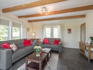 a living room with two gray couches and red pillows at Strathmaddie Farm Cottage in Palnure