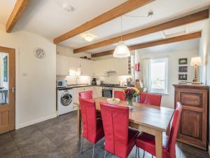 a kitchen with a wooden table and red chairs at Strathmaddie Farm Cottage in Palnure +16 photos