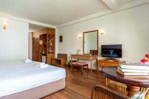a bedroom with a bed and a desk with a television at Sirin Hotel Hua Hin in Hua Hin