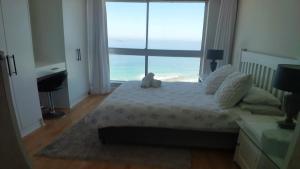 a bedroom with a bed with a teddy bear on it at Blouberg Heights in Cape Town