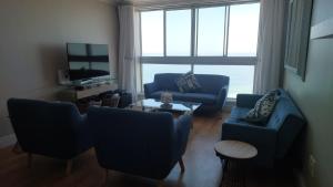 a living room with two blue couches and a tv at Blouberg Heights in Cape Town