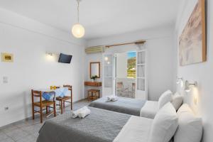 una habitación de hotel con dos camas, una mesa y sillas en Seample studios, en Chrissi Akti