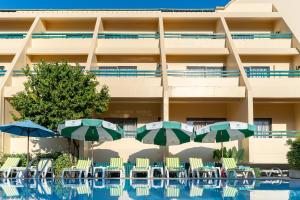 a hotel with chairs and umbrellas next to a swimming pool at Sirin Hotel Hua Hin in Hua Hin
