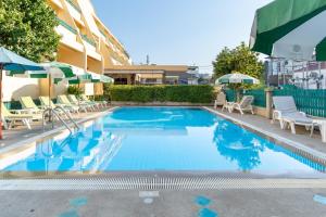 a swimming pool with chairs and umbrellas next to a building at Sirin Hotel Hua Hin in Hua Hin