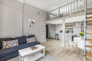 a living room with a blue couch and a kitchen at Well Appointed Garden Condo in Kensington Olympia in London