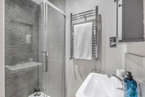 a white bathroom with a shower and a sink at Well Appointed Garden Condo in Kensington Olympia in London +15 photos