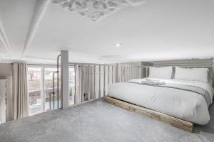 a white bedroom with a large bed and a balcony at Well Appointed Garden Condo in Kensington Olympia in London